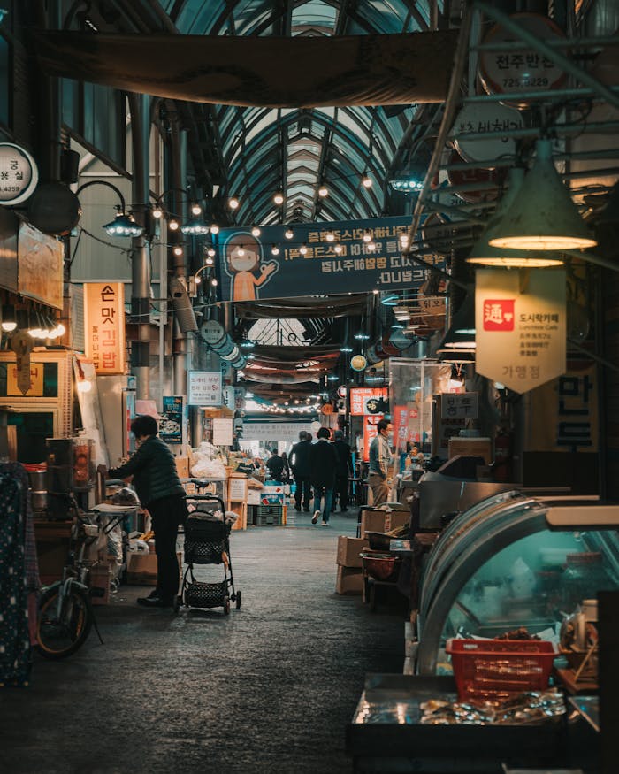 A lively scene inside a traditional market in Seoul, showcasing a variety of stalls and people shopping.
